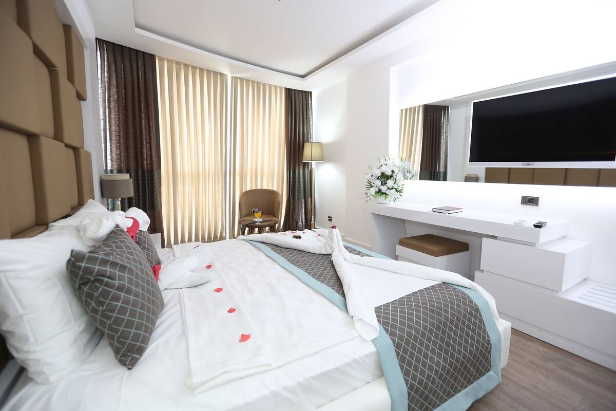 Ein Hotelzimmer mit Bett, Schreibtisch, Fernseher und Stuhl.