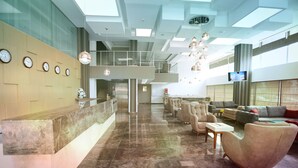 A spacious lobby with a reception desk, multiple seating areas, and a large TV screen. - Elips Royal Hotel & Spa (Antalya)