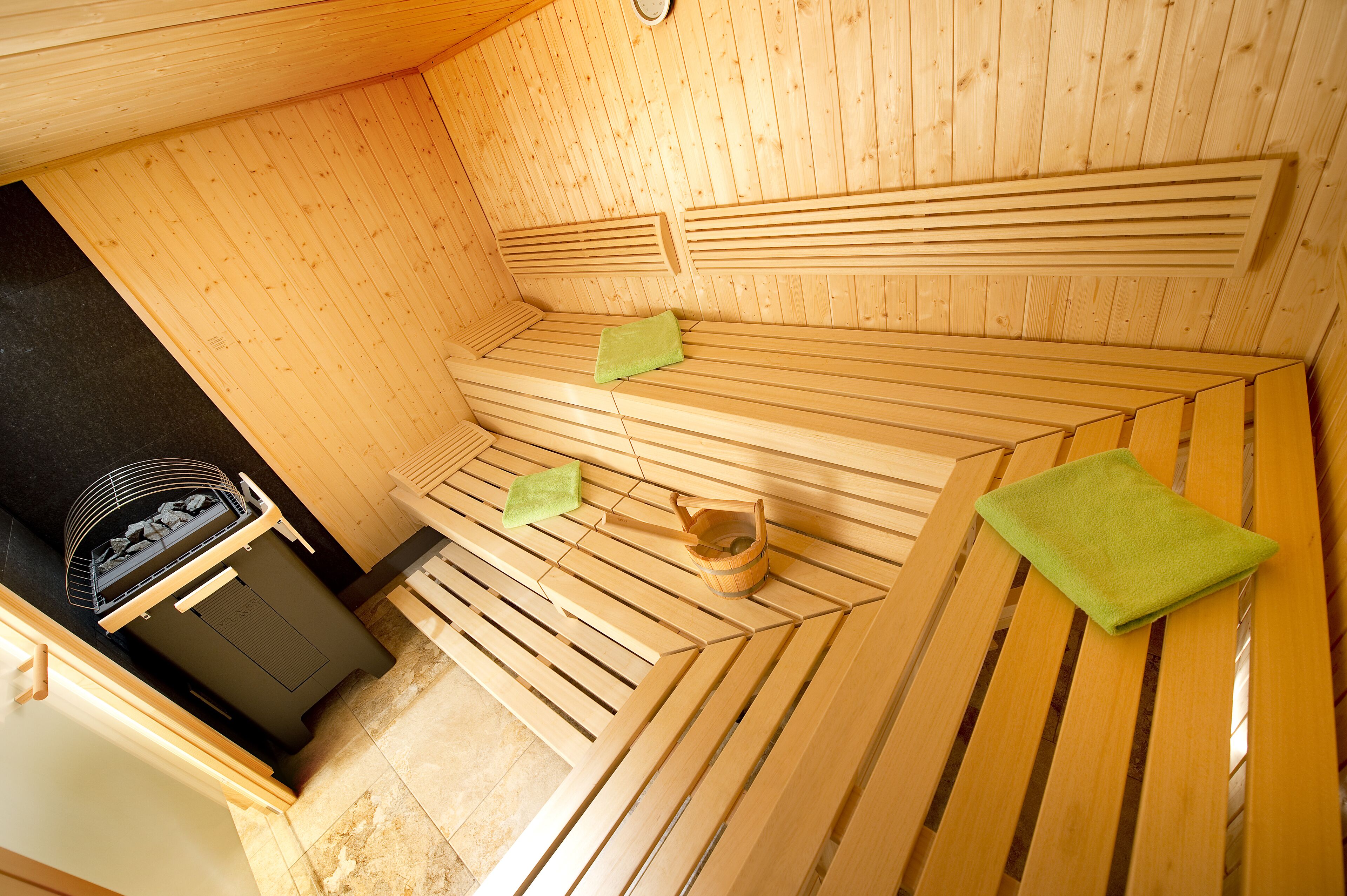 Un sauna avec des bancs en bois et un chauffage intégré dans un des bancs.