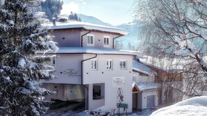 A two-story building with a snow-covered roof and a sign indicating it is a 'Dorfwuel Apartment'. - Dorfjuwel Appartements (Wildschönau)