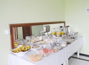 Una mesa de buffet con diversas opciones de comida y bebidas, entre ellas frutas, cereales y jugos.