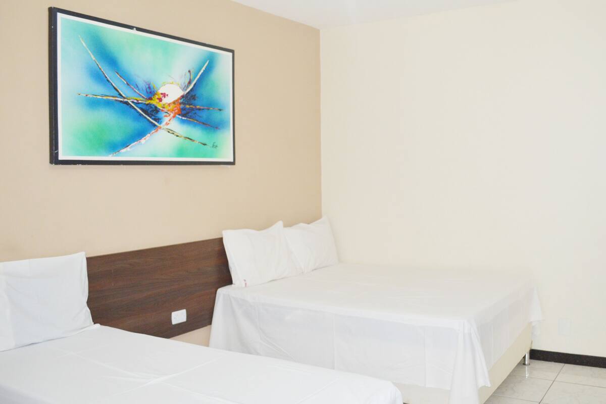 Habitación de hotel con dos camas, un cuadro abstracto grande en la pared y un techo blanco sencillo.