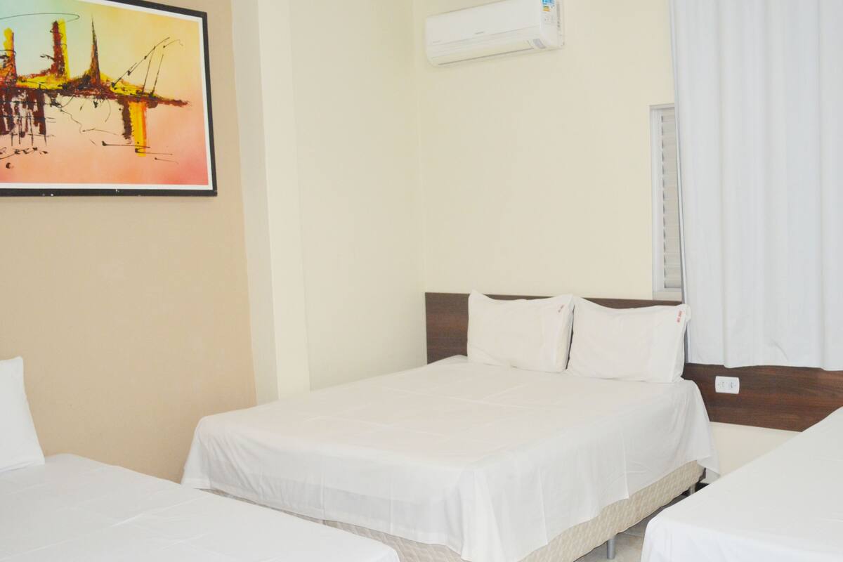 Una habitación de hotel con dos camas, un cuadro en la pared y un equipo de aire acondicionado.