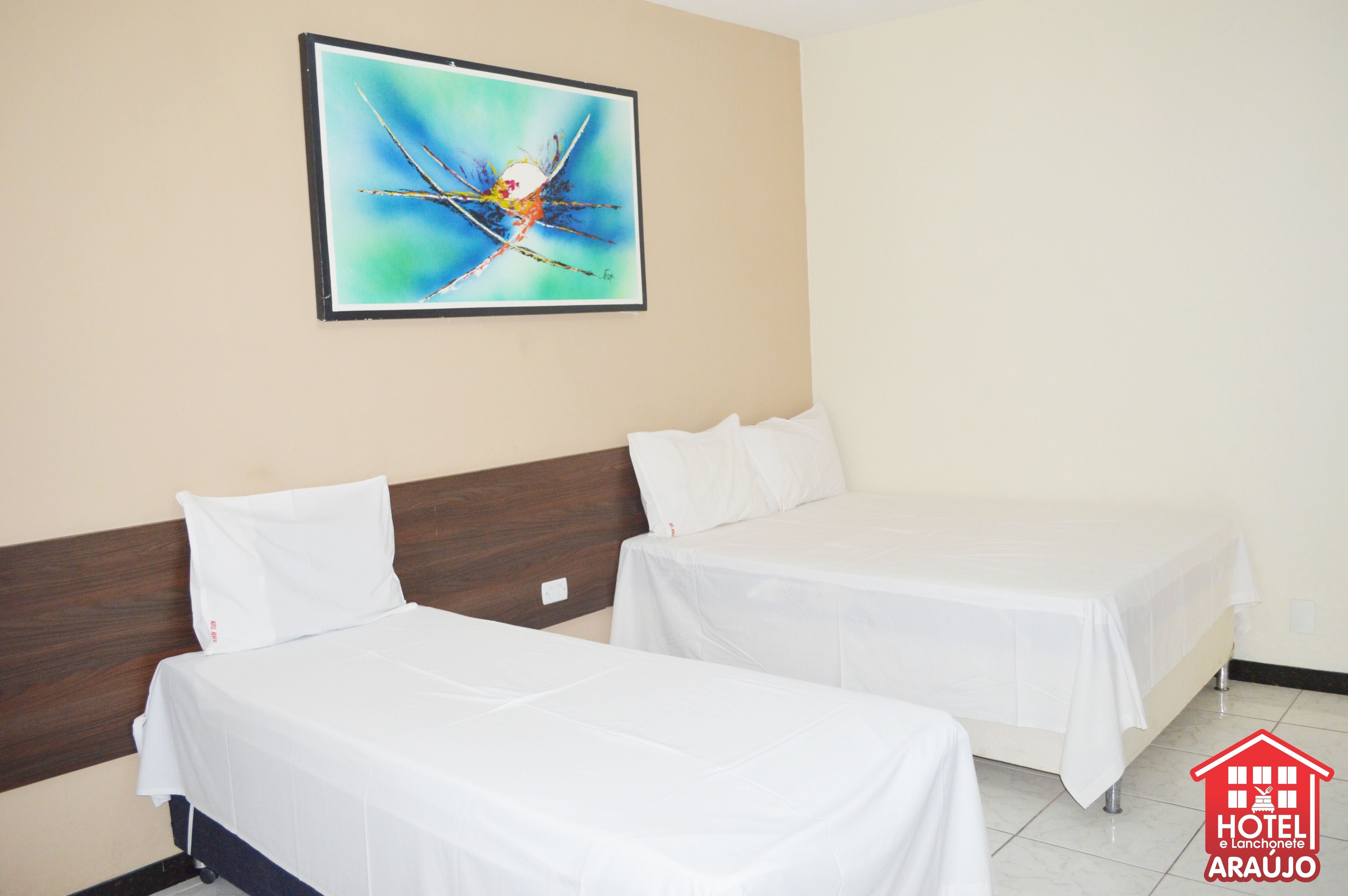 Habitación de hotel con dos camas individuales, cabecero de madera, cuadro abstracto enmarcado en la pared y un logotipo en la esquina inferior derecha.