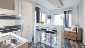 A modern kitchen with a built-in stove, a sink, and a bar area with stools. - Boutique Apartments Blitz (Bibinje)