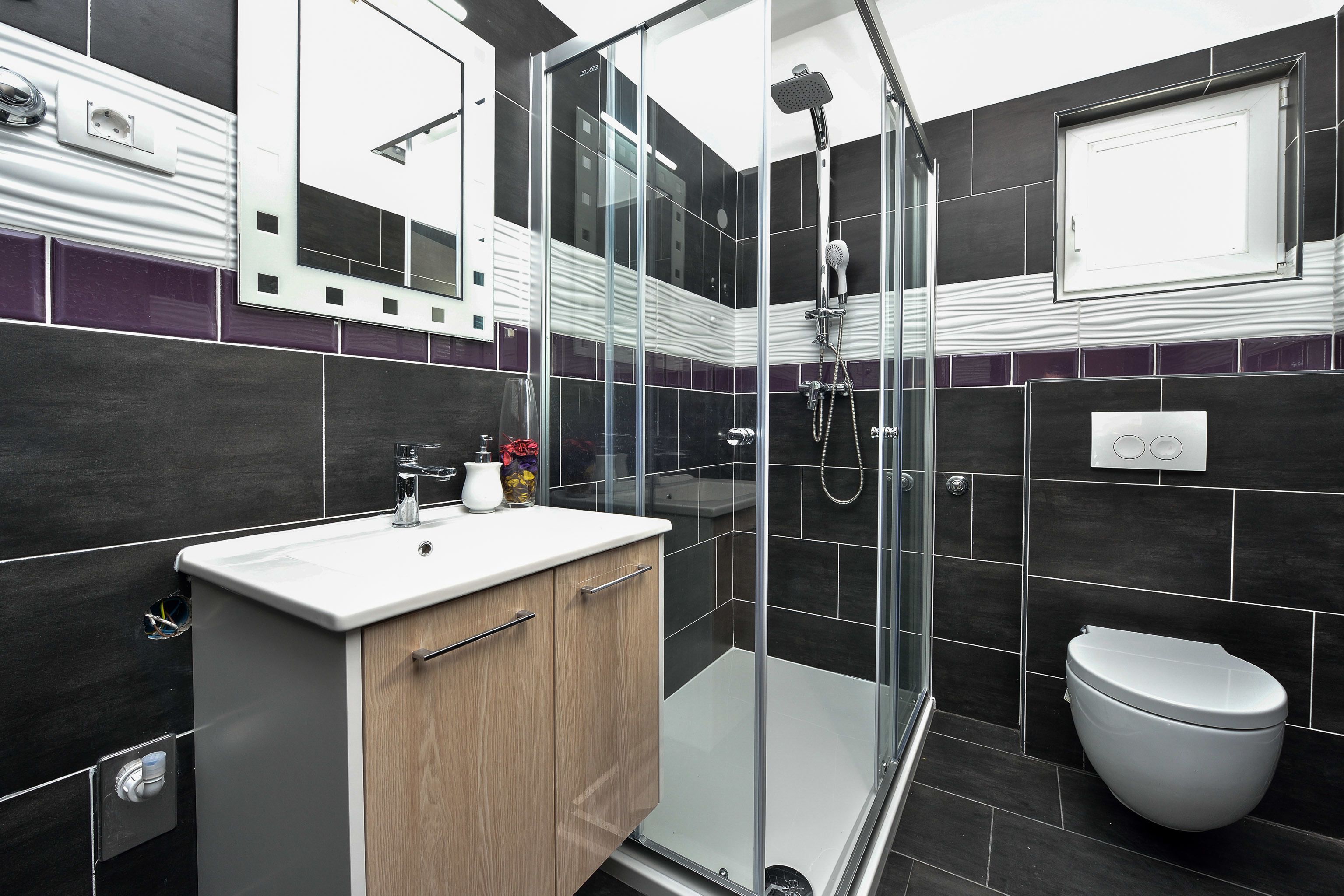 A modern bathroom with a glass shower enclosure, a white sink, and a toilet.