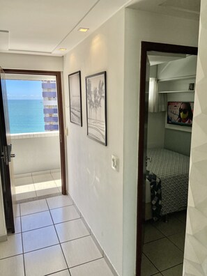 A hotel room with a balcony, a bed with a patterned bedspread, and two framed pictures on the wall.
