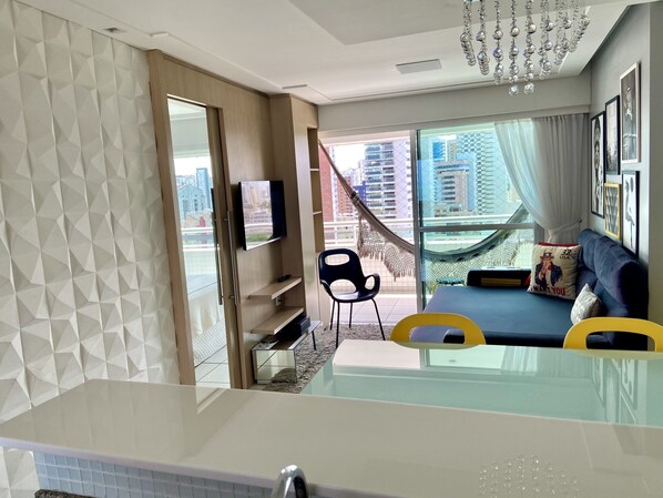 Una sala de estar moderna con un sofá, televisión y vistas a la ciudad.