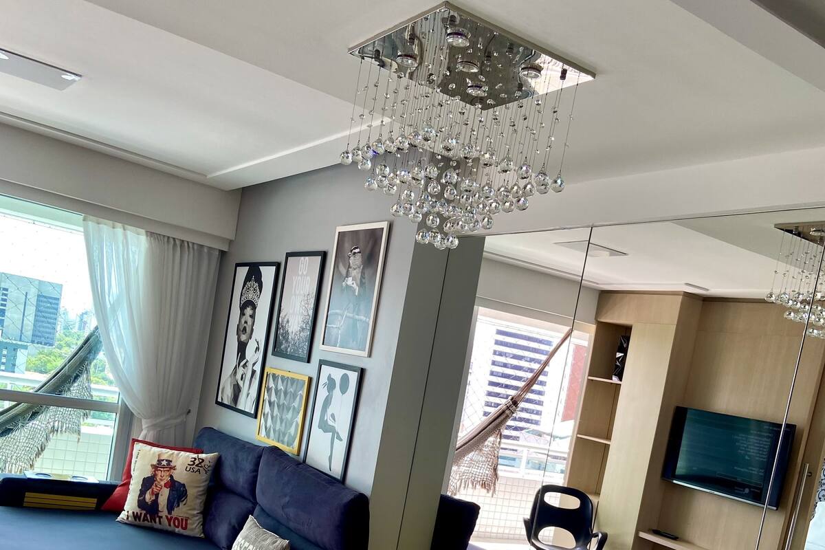 Ein modernes Wohnzimmer mit einem Glastisch, einem blauen Sofa und einer Chandelüster.