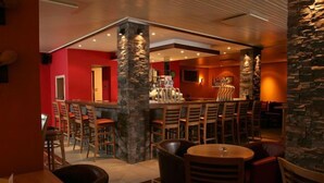 Un restaurant doté d’un bar, de chaises en bois et d’un pilier en pierre.