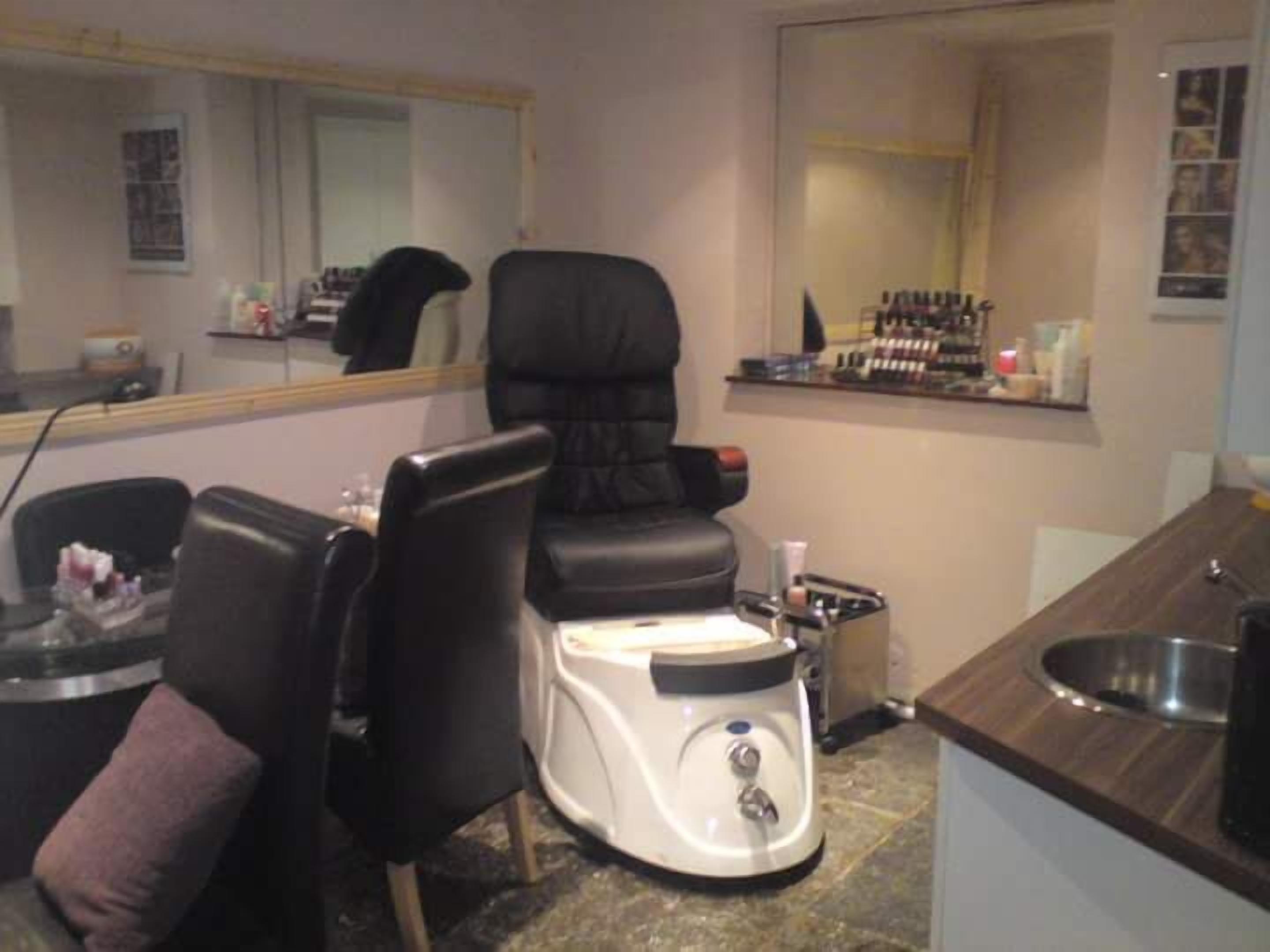 A room with a massage chair, a small table with a bottle, and a mirror.