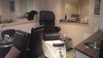 A room with a massage chair, a small table with a bottle, and a mirror.