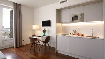 A modern kitchen with a built-in microwave, a dining area with two chairs, and a view of the city through a window.