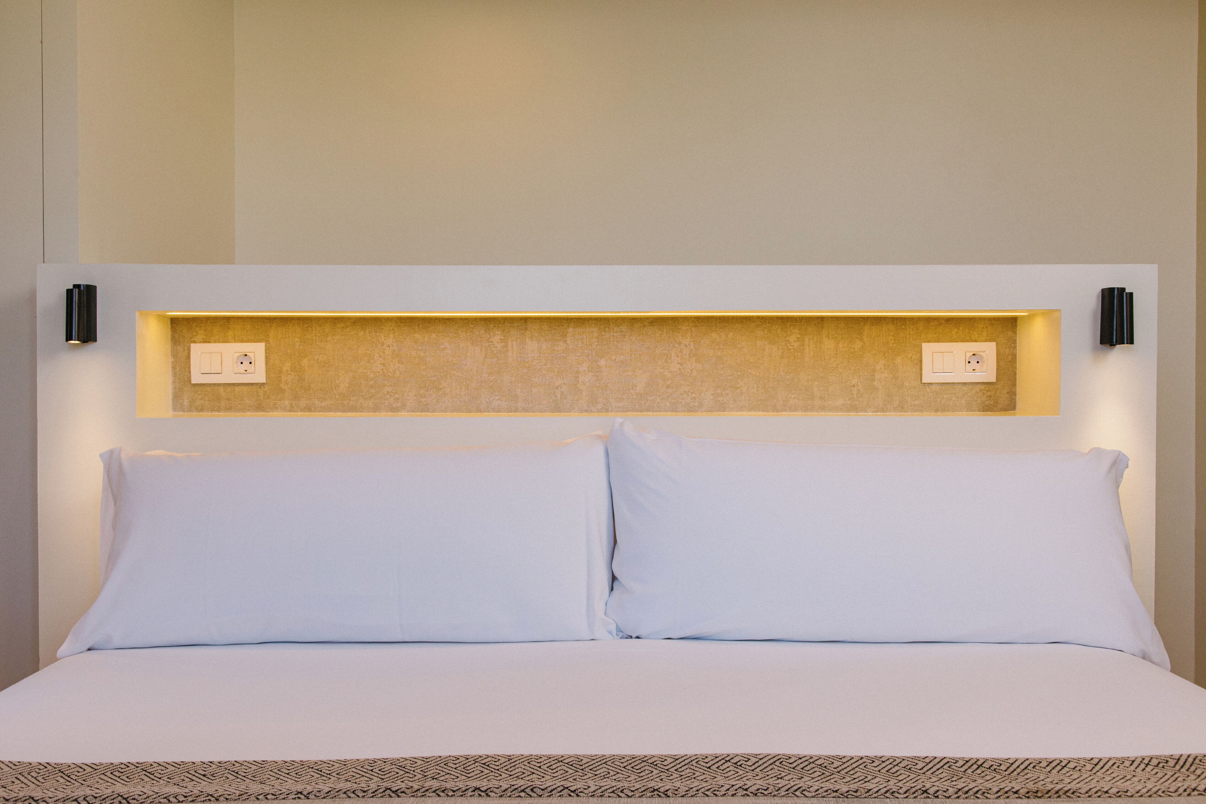 A neatly made bed with white linens and a patterned bedspread.