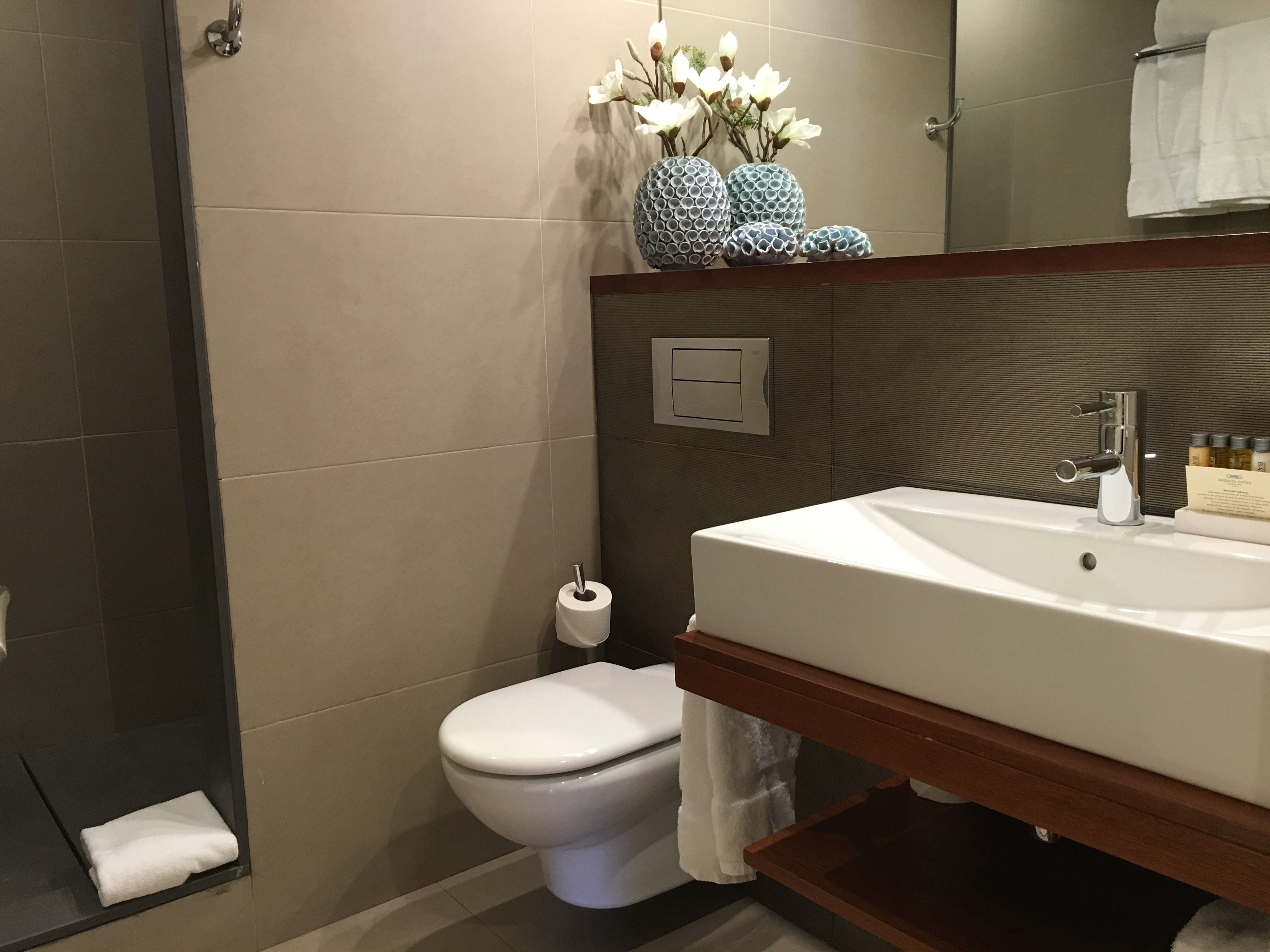 A modern bathroom with a white sink, a toilet, and a shower area.