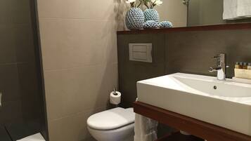 Un baño moderno con un lavabo blanco, un inodoro y una zona de ducha.