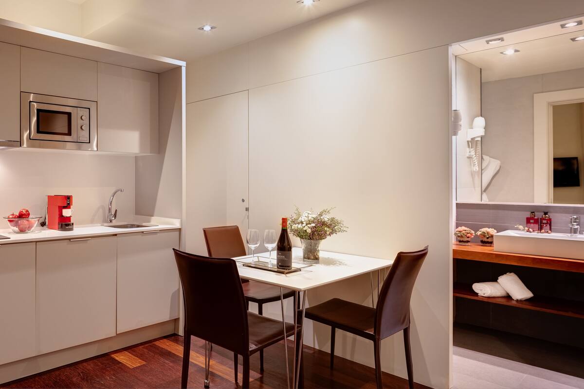 Una cocina moderna con microondas integrado, un fregadero y una zona de comedor con dos sillas y una mesa.