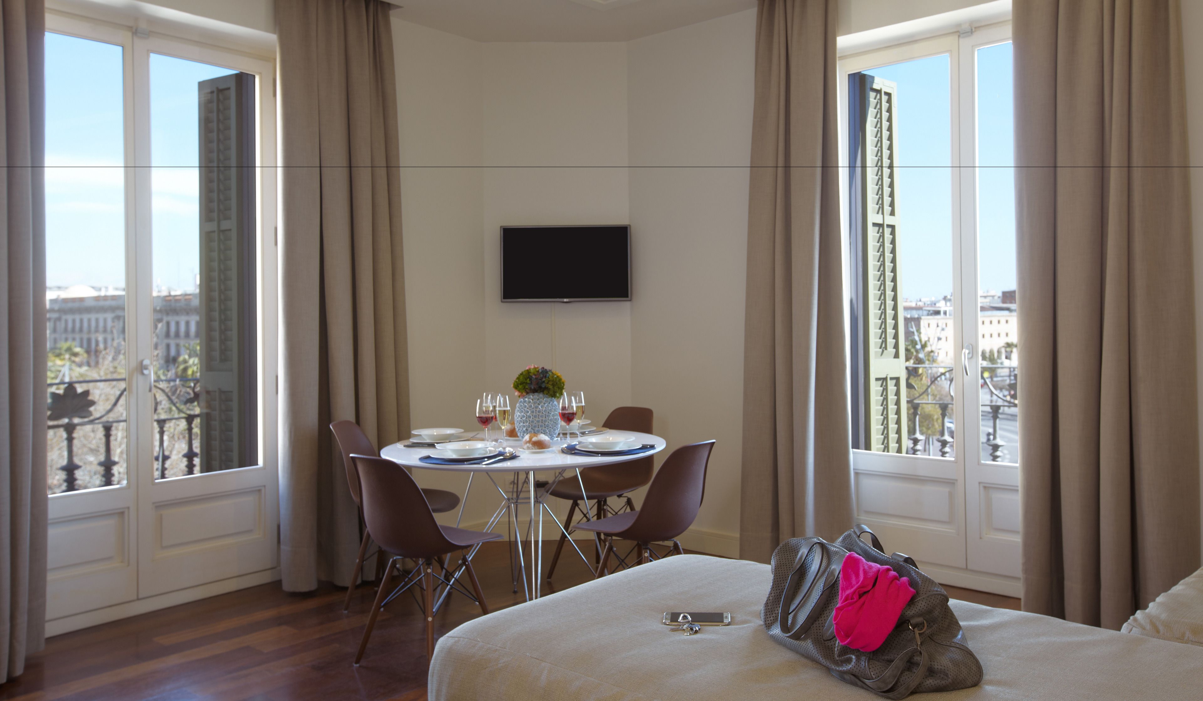 A hotel room with a dining area, a bed, and a TV.