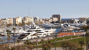 Un puerto deportivo con varios yates amarrados, rodeado de edificios y palmeras.