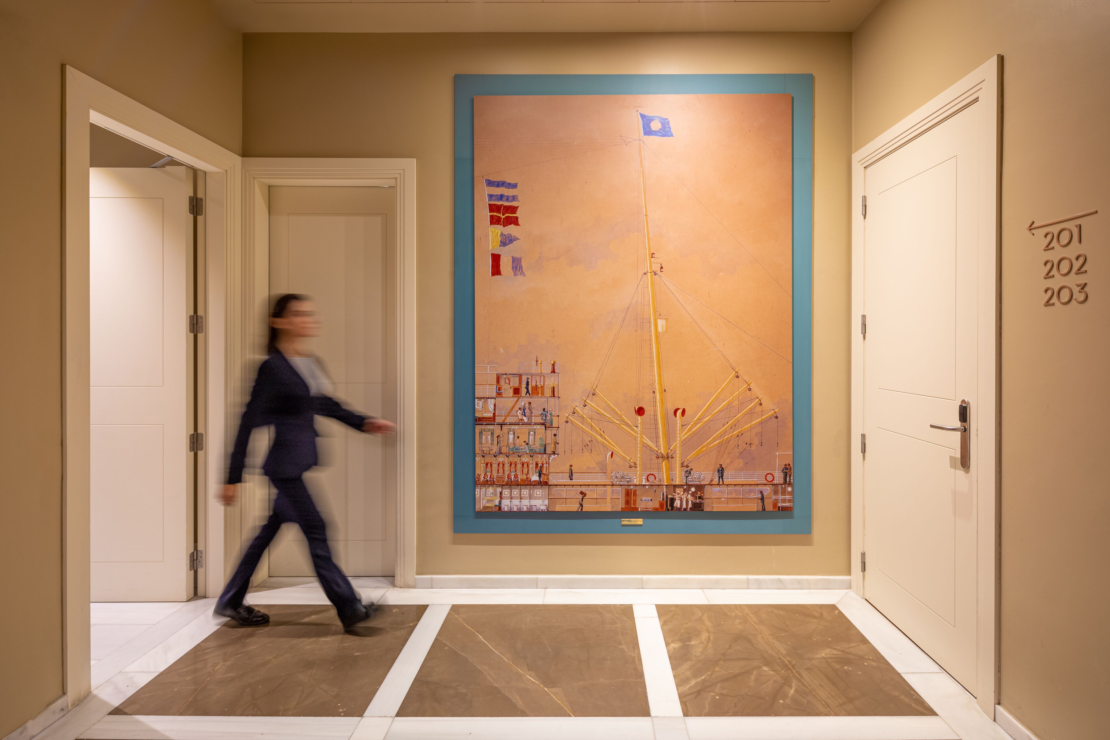 A hallway with a large mural, numbered doors, and a patterned floor.