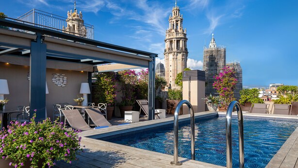 Piscina en la azotea con sillones de descanso y vistas a edificios históricos.
