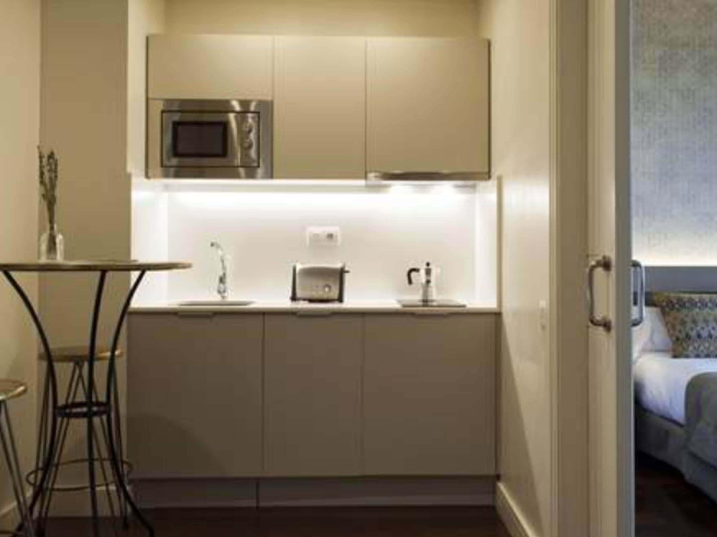 A compact kitchenette with a microwave, sink, and a small table.