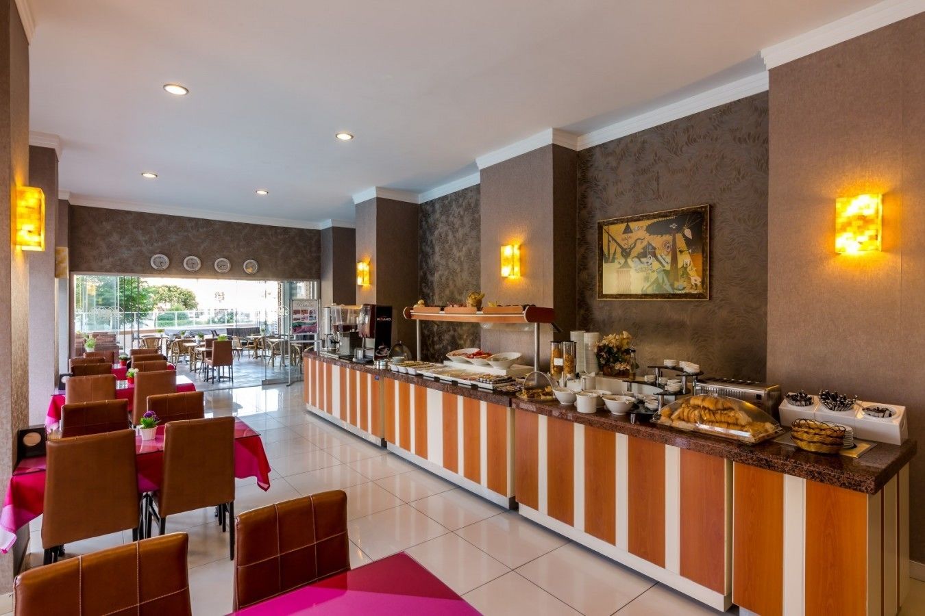 A hotel lobby with a buffet area, seating arrangements, and a large window providing a view of the outdoors.