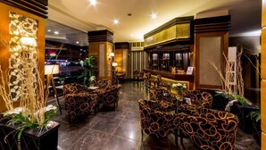 Un restaurant avec des chaises à motifs, un coin bar et des plantes décoratives.