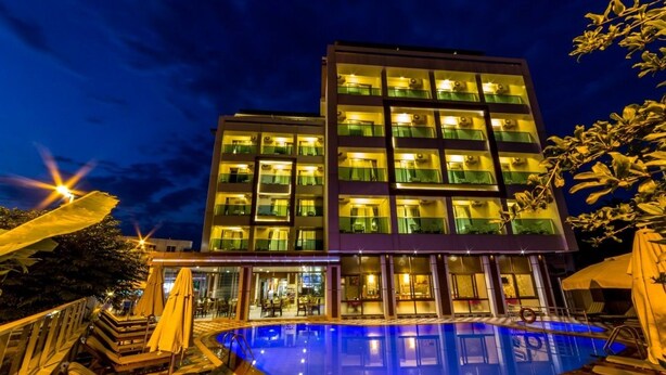 Un hôtel moderne doté d’une piscine, d’un espace extérieur aménagé et d’une façade bien éclairée.