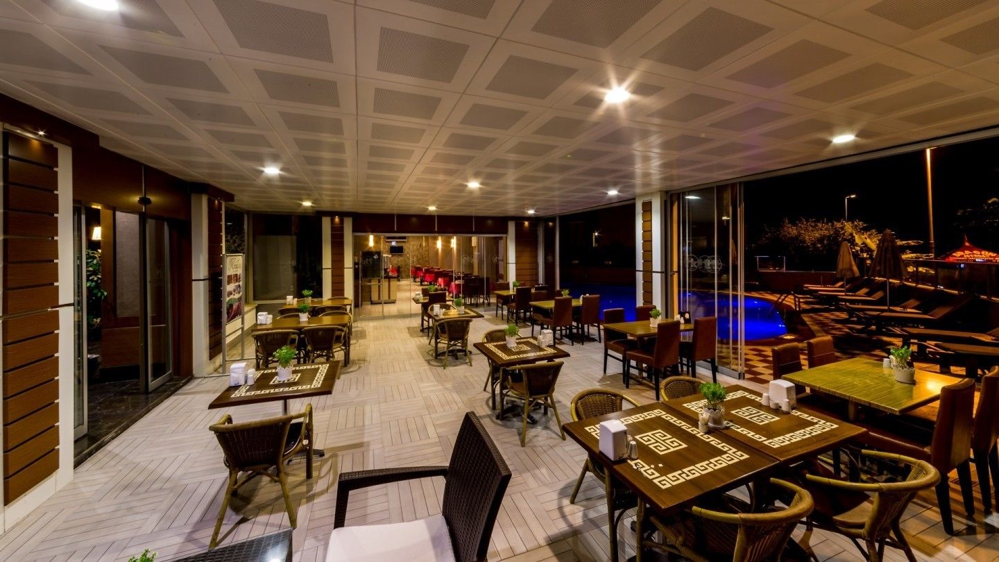 An indoor dining area with tables and chairs, a pool, and large windows.