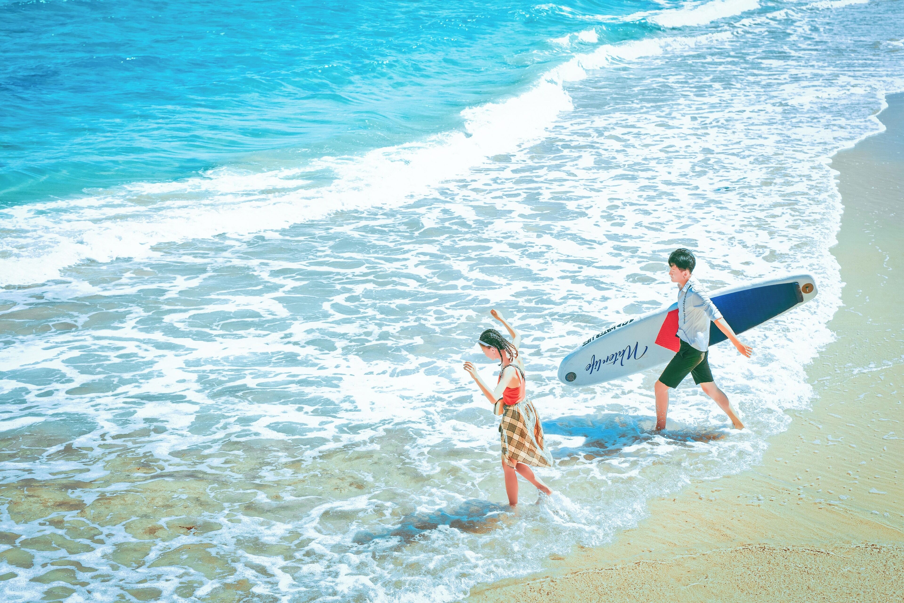 A beach scene with clear blue water and waves.