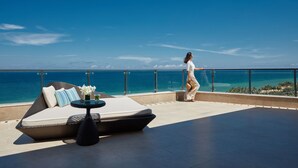 A balcony with a sofa, a small table, and a view of the sea. - Marriott Resort Xiangshui Bay (Lingshui)