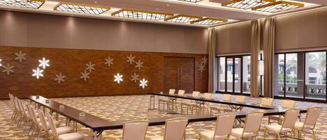 A conference room with a long table and chairs, large windows, and a patterned carpet.