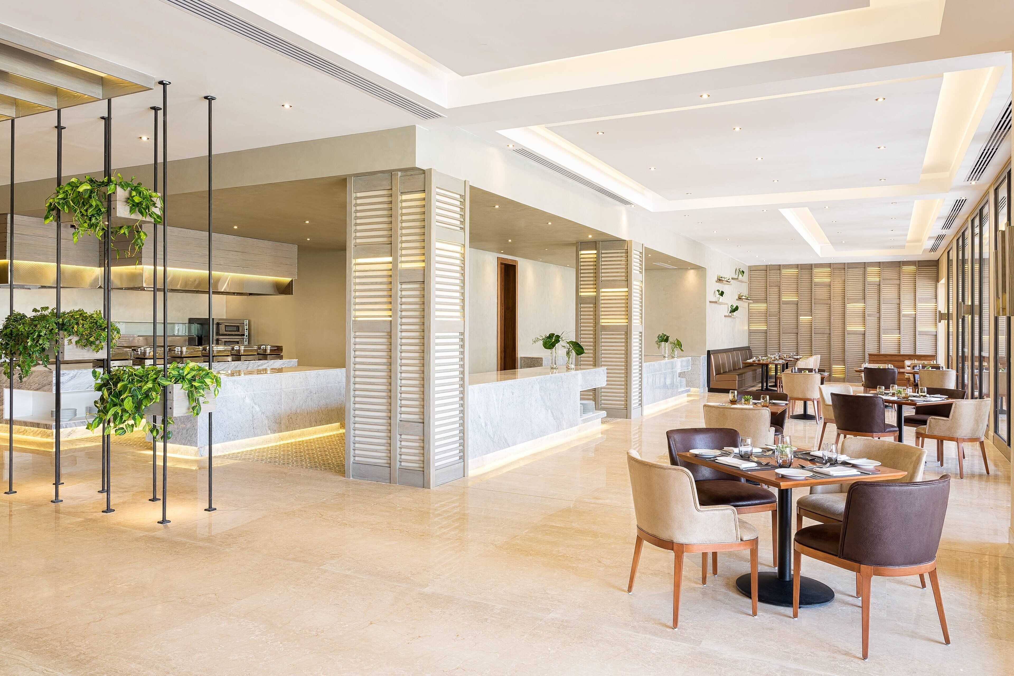 En modern hotellobby med en receptionsdisk, en sittgrupp och ett kök i bakgrunden.