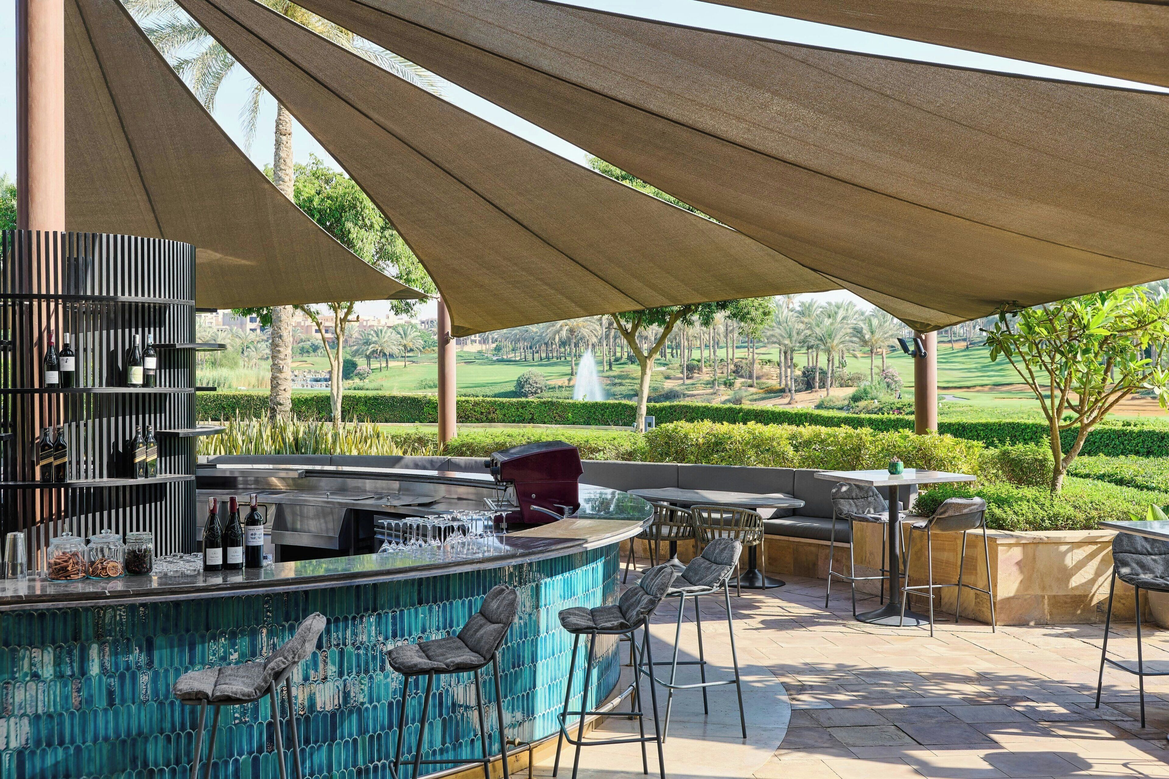 An outdoor bar area with a pool, bar stools, and a grill.