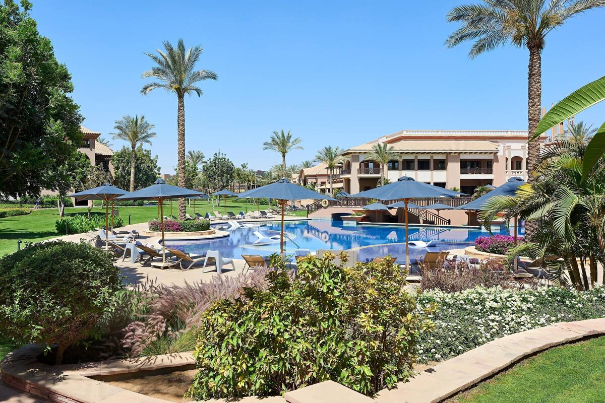 Un resort con piscina, tumbonas y palmeras.