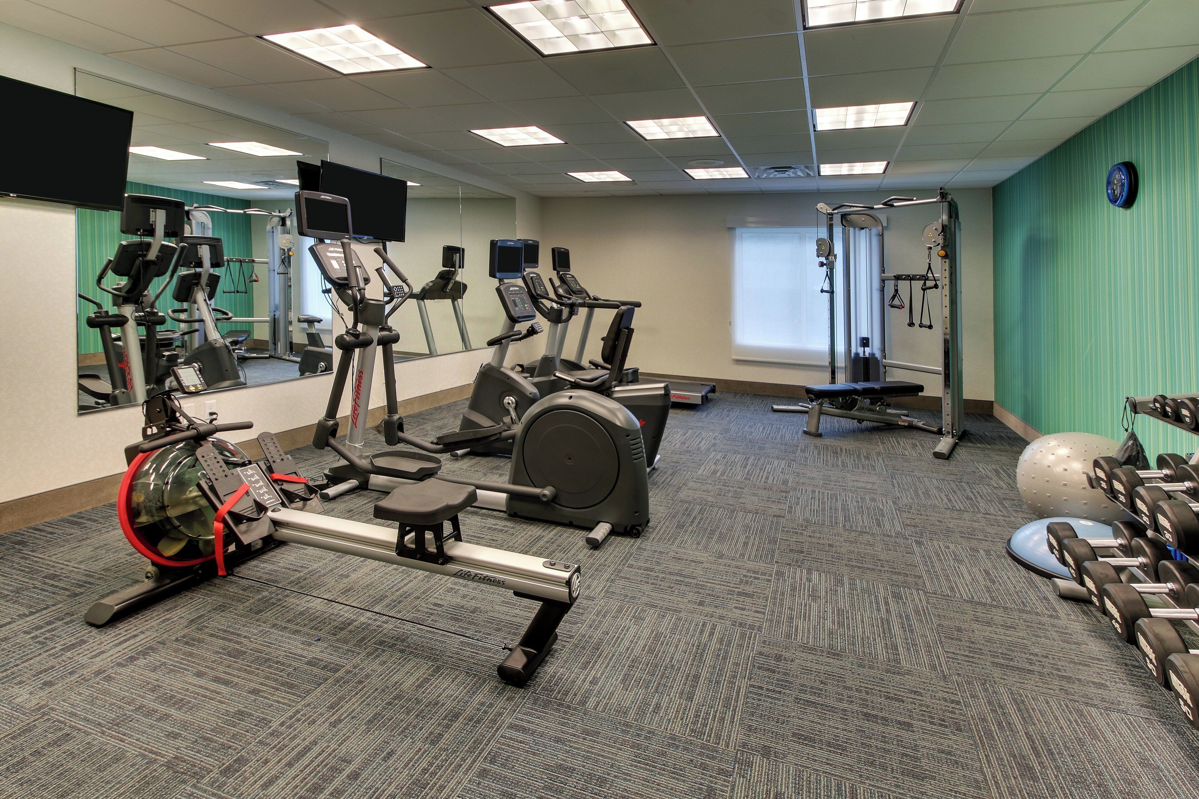 Une salle de sport équipée de divers appareils d’exercice, notamment des tapis de course, des vélos d’appartement et des poids.