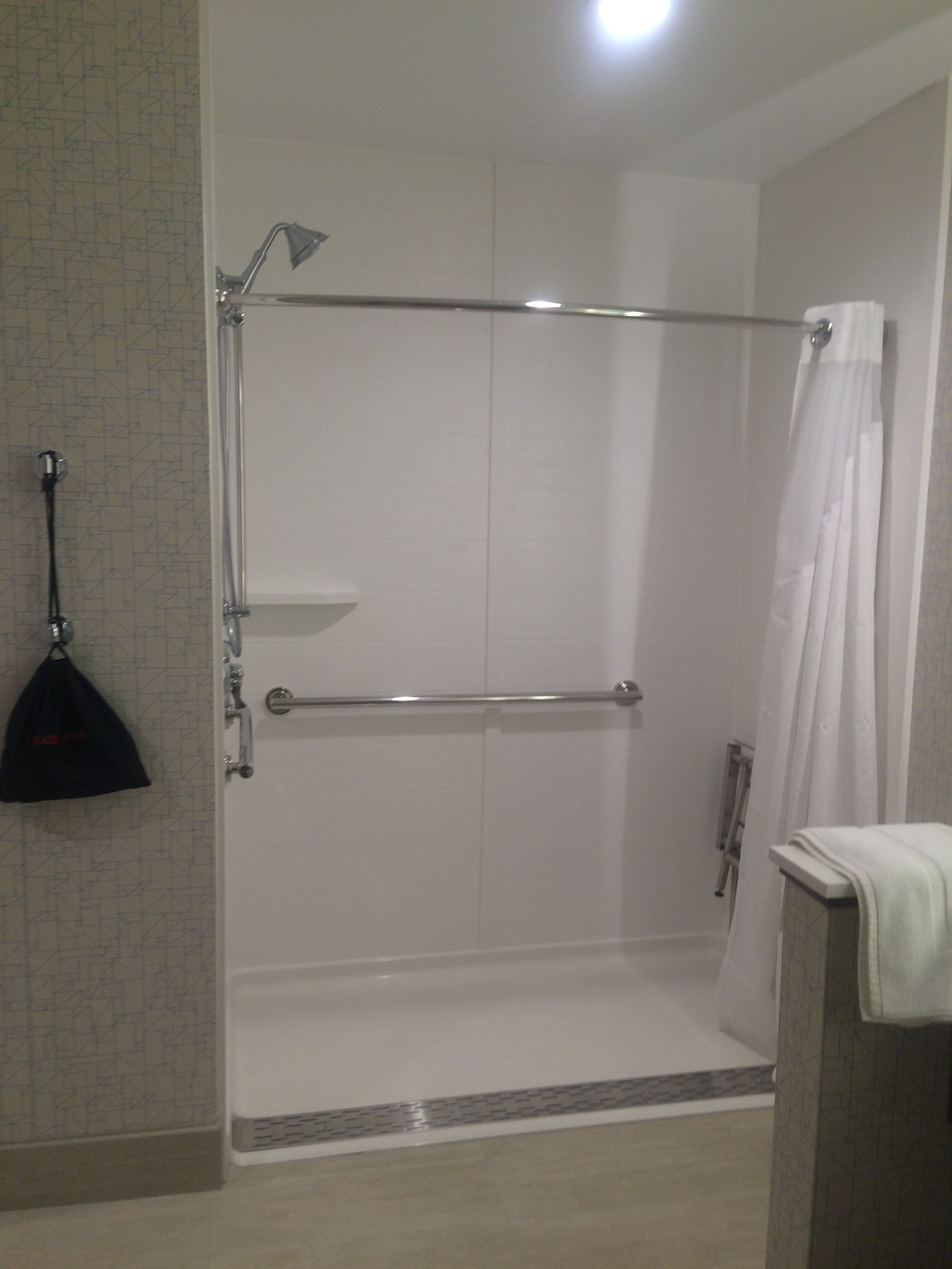 A walk-in shower with a glass door, a towel rack, and a shower curtain.