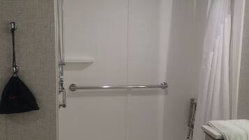A walk-in shower with a glass door, a towel rack, and a shower curtain.