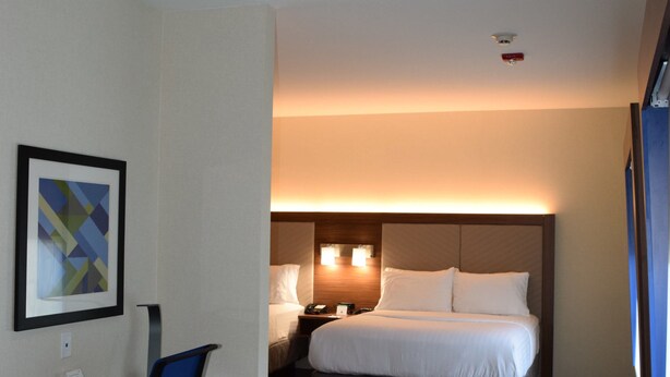 Habitación de hotel con cama, escritorio, silla y un cuadro en la pared.