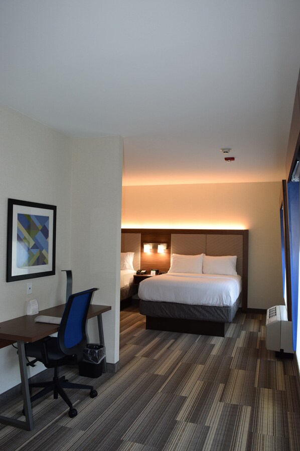 Een hotelkamer met een bed, bureau, stoel en een lijst met een afbeelding aan de muur.