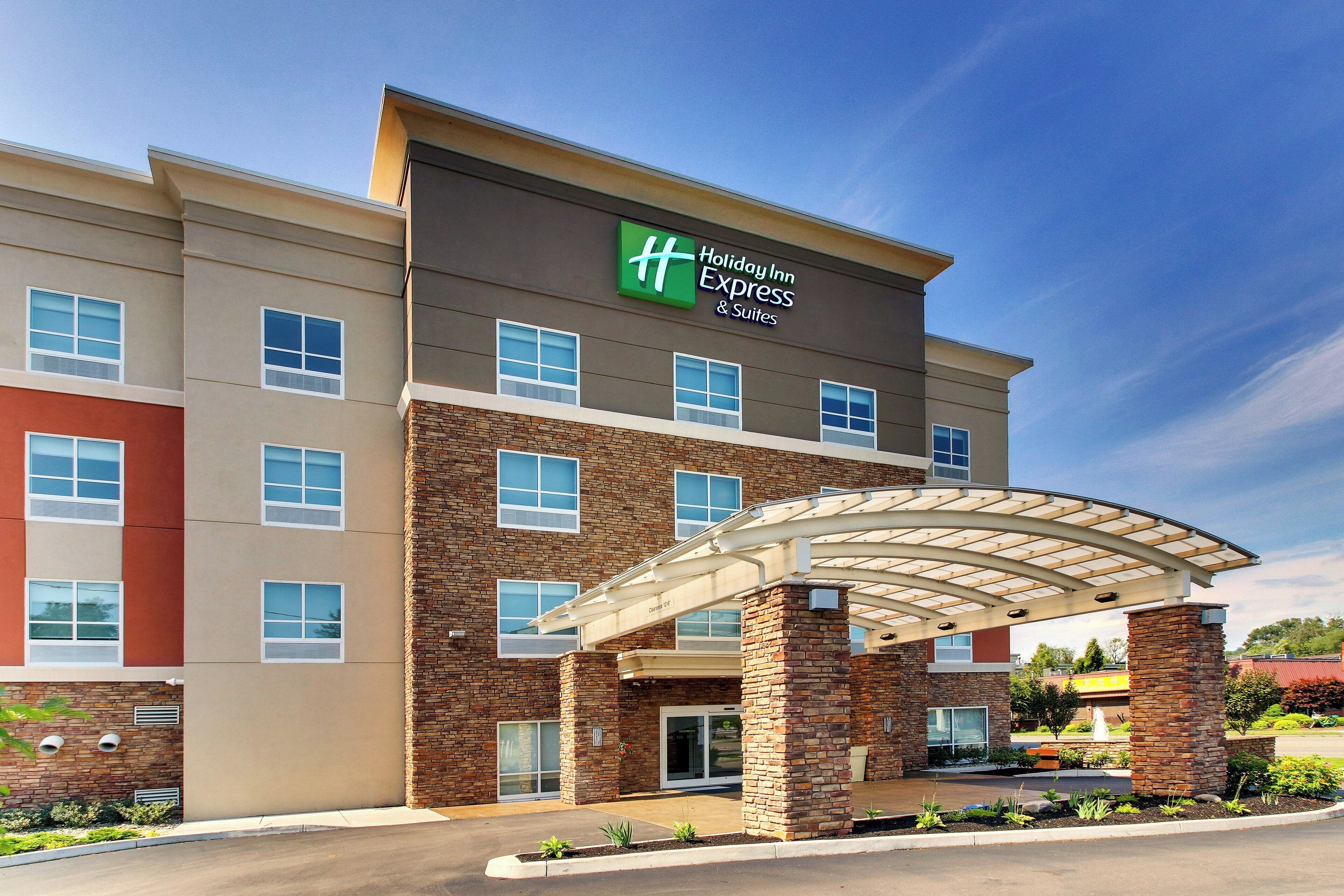 A Holiday Inn Express & Suites building with a covered entrance, multiple windows, and a brick facade.
