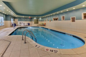Una piscina interior con agua cristalina, paredes de azulejos y techo azul.