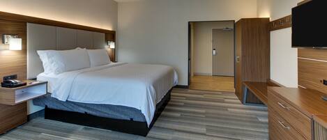 A modern hotel room with a large bed, bedside tables, a flat-screen TV, and a wooden wardrobe.