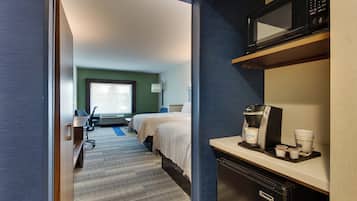 Une chambre d’hôtel avec un lit, un bureau équipé d’une machine à café, d’un four à micro-ondes et d’une fenêtre.