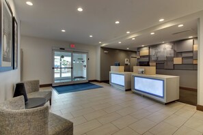 A hotel reception area with a glass door entrance, a reception desk, and a seating area with chairs. - Holiday Inn Express & Suites Ithaca by IHG (Ithaca)