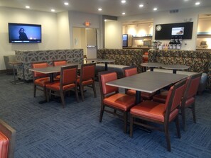 A restaurant with booths and tables, a TV screen, and a coffee station.