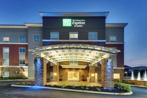 A Holiday Inn Express & Suites hotel with a covered entrance and a landscaped front yard.