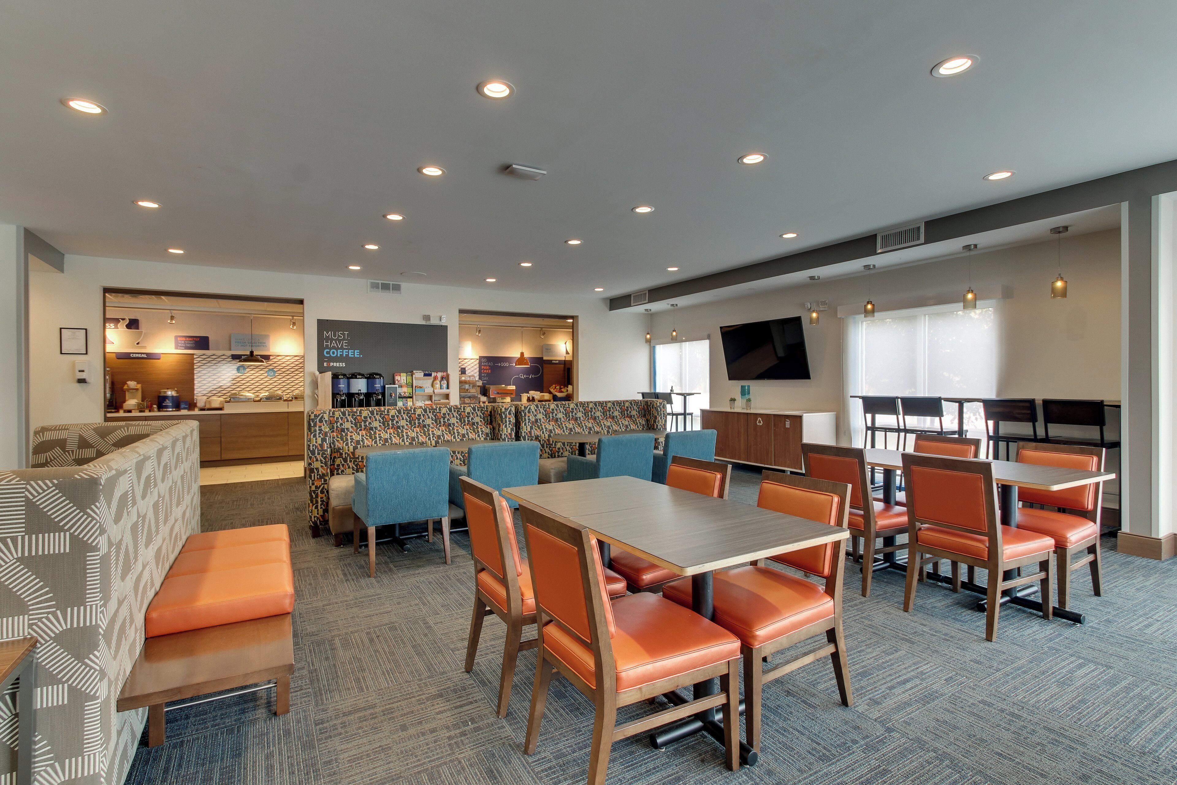 A hotel lobby with seating areas, a coffee bar, and a television screen.