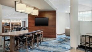 A modern conference room with a long table, chairs, a flat-screen TV, and a wooden accent wall.